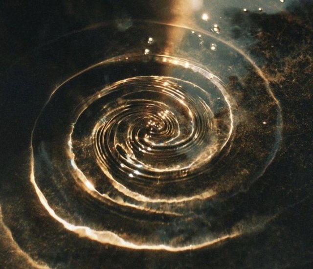 Golden light spiraling on dark water