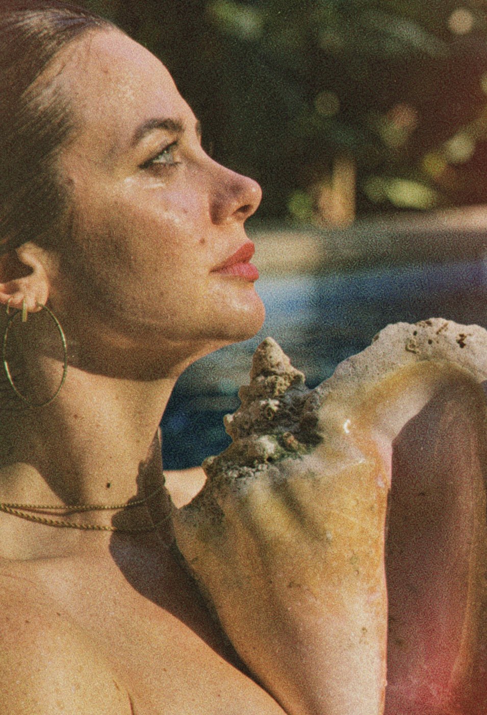 Hannah in profile, sunlit, holding a conch shell